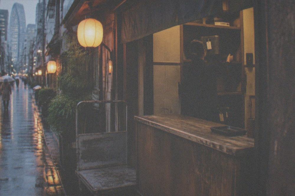 A shop counter in Tokyo where a staff member accepts a suitcase for storage behind the till