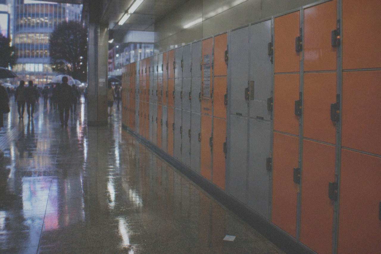 Rows of orange and grey coin lockers along a Tokyo station corridor, some doors shut and locked